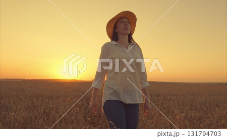 A Serene and Elegant Woman walking Gracefully Amidst a Wheat Field during a Beautiful Sunset 131794703