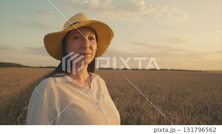 A Woman in a Wheat Field at Sunset, with radiant colors lighting up the serene landscape 131796562