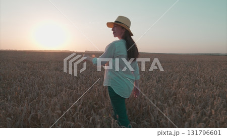 A Stunning and Beautiful Sunset in the Golden Wheat Field Featuring a Happy Woman 131796601