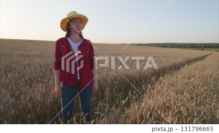 A woman in a straw hat smiles in a wheat field, capturing summer and natures beauty 131796665