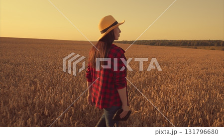 A serene woman standing gracefully in a vast wheat field during a captivating sunset A serene woman standing gracefully in a vast wheat field during a captivating sunset 131796680