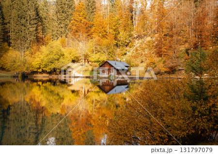Autumn cabin by a lake reflecting colorful trees Autumn cabin by a lake reflecting colorful trees 131797079