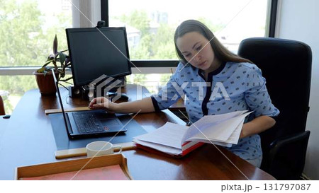 Focused businesswoman using technology to improve productivity while working at desk in bright office with large windows 131797087