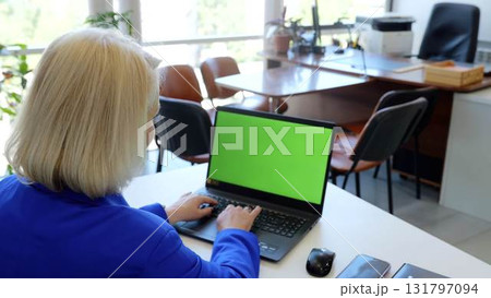 Experienced female executive using a laptop with a green screen, chroma key, in a contemporary office, providing options for tailored content and presentations Experienced female executive using a laptop with a green screen, chroma key, in a contemporary office, providing options for tailored content and presentations 131797094