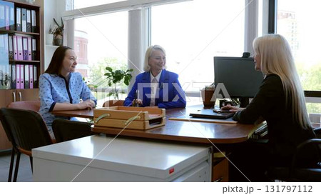 Three female executives collaborating in a contemporary office setting, actively participating in a productive work meeting and discussing business projects Three female executives collaborating in a contemporary office setting, actively participating in a productive work meeting and discussing business projects 131797112