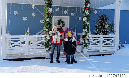Festive family gathers on a snowy porch, exuding happiness and unity during the holiday season. New Year's Eve with family. Christmas Day with the family Festive family gathers on a snowy porch, exuding happiness and unity during the holiday season. New Year's Eve with family. Christmas Day with the family 131797133
