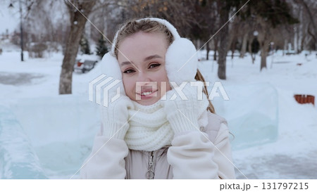 Cheerful woman in winter accessories smiling brightly, walking through snow covered park, experiencing seasonal joy and crisp winter landscape Cheerful woman in winter accessories smiling brightly, walking through snow covered park, experiencing seasonal joy and crisp winter landscape 131797215
