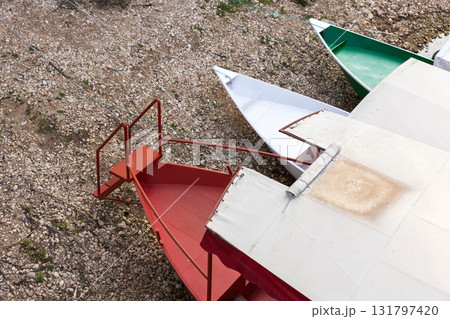 Colorful pleasure boats with a white canopy rest at a shoreline Colorful pleasure boats with a white canopy rest at a shoreline 131797420