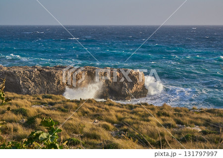 Crashing waves on rocky Malta coast with limestone cliff and blue Mediterranean Crashing waves on rocky Malta coast with limestone cliff and blue Mediterranean 131797997