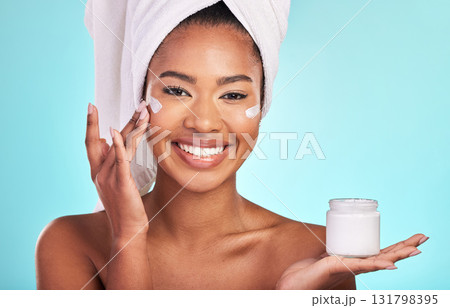 Skincare, beauty and portrait of black woman with cream, towel and smile in bathroom routine or skin glow on blue background. Cosmetics, facial and African model with lotion product in hand in studio Skincare, beauty and portrait of black woman with cream, towel and smile in bathroom routine or skin glow on blue background. Cosmetics, facial and African model with lotion product in hand in studio 131798395