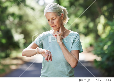 Senior woman, watch and pulse outdoor for exercise on run, workout and training on road for fitness. Elderly female person check cardio progress time for health and wellness while running in nature 131798533