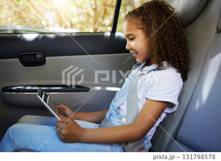 Happy, road trip and a child in a car with a tablet for a movie, cartoons or video. Smile, travel and a girl sitting in a vehicle with tech, streaming online and enjoying a film for entertainment Happy, road trip and a child in a car with a tablet for a movie, cartoons or video. Smile, travel and a girl sitting in a vehicle with tech, streaming online and enjoying a film for entertainment 131798578
