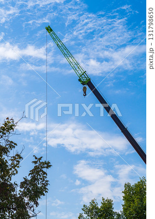 Photo of a construction truck crane, the retractable boom of which is lengthened at the end by a telescopic extension device - a jib. Vertical shot against blue sky background with small clouds Photo of a construction truck crane, the retractable boom of which is lengthened at the end by a telescopic extension device - a jib. Vertical shot against blue sky background with small clouds 131798650