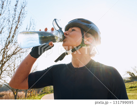 Woman drinking water, bottle and cycling with fitness outdoor, helmet for safety and health with hydration. Athlete, biking and female with healthy and active lifestyle, wellness and sports training Woman drinking water, bottle and cycling with fitness outdoor, helmet for safety and health with hydration. Athlete, biking and female with healthy and active lifestyle, wellness and sports training 131799095