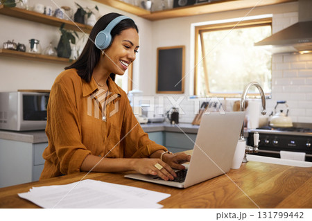 Home, remote work and business woman on laptop for research project, strategy and planning in kitchen. Freelancer, smile and girl with headphones for music with documents, computer and working online Home, remote work and business woman on laptop for research project, strategy and planning in kitchen. Freelancer, smile and girl with headphones for music with documents, computer and working online 131799442