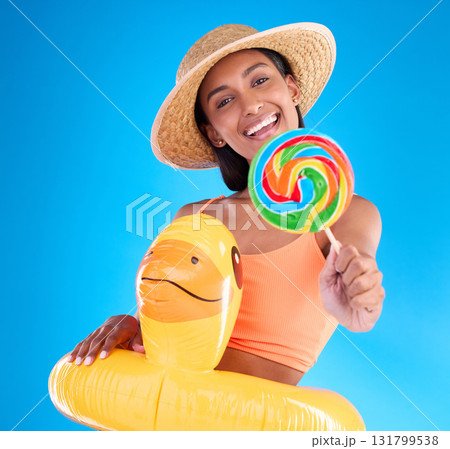 Portrait, lollipop and inflatable duck with a woman on a blue background in studio ready for summer swimming. Happy, travel and vacation with an attractive young female looking excited to relax Portrait, lollipop and inflatable duck with a woman on a blue background in studio ready for summer swimming. Happy, travel and vacation with an attractive young female looking excited to relax 131799538