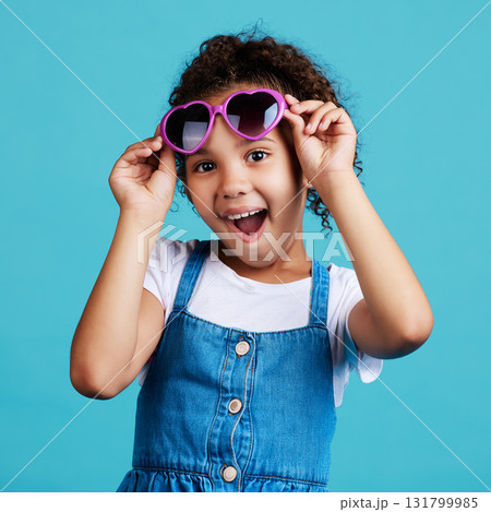 Happy, sunglasses and portrait of a child in studio with a positive, shocked and excited face expression. Happiness, surprise and girl kid model with funky, trendy and cool glasses by blue background 131799985
