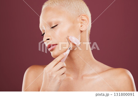 Cosmetics, skincare and woman with roller, face detox and morning routine for wellness or soft skin on studio background. Female, lady and rose quartz for luxury, salon treatment or makeup for facial 131800091