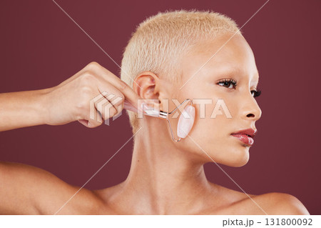 Face skincare, jade roller and woman in studio isolated on a red background for dermatology. Beauty, cosmetics and female model with product or rose quartz stone for facial treatment and healthy skin Face skincare, jade roller and woman in studio isolated on a red background for dermatology. Beauty, cosmetics and female model with product or rose quartz stone for facial treatment and healthy skin 131800092