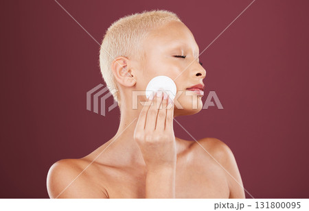 Face, skincare and woman with cotton pad in studio isolated on a red background. Beauty dermatology, eyes closed and female model with facial product for cleaning makeup, cosmetics and healthy skin. Face, skincare and woman with cotton pad in studio isolated on a red background. Beauty dermatology, eyes closed and female model with facial product for cleaning makeup, cosmetics and healthy skin. 131800095