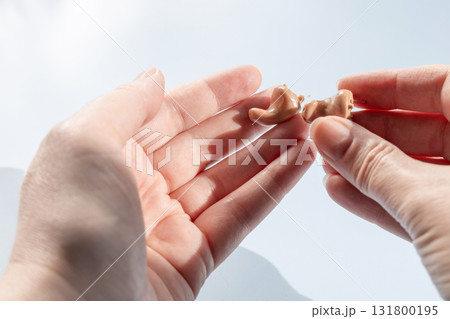Doctor holding modern hearing aid in his hand 131800195