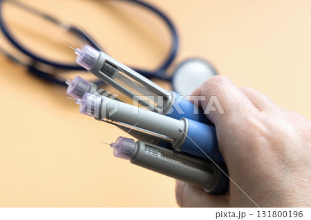 Women's hands holding Insulin injection pen for diabetics and weight loss. 131800196