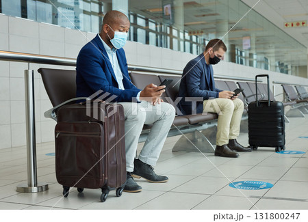 Social distance, suitcase and businessmen waiting in the airport and networking with cellphone. Face mask, luggage and professional male employees sitting with travel restrictions browsing on a phone Social distance, suitcase and businessmen waiting in the airport and networking with cellphone. Face mask, luggage and professional male employees sitting with travel restrictions browsing on a phone 131800247