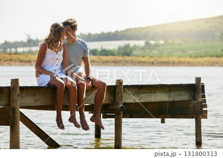 Couple sitting on jetty, relax by lake and summer, travel and adventure, love and care outdoor. People in relationship, trust and bonding on vacation, man and woman with freedom and forehead touch 131800313