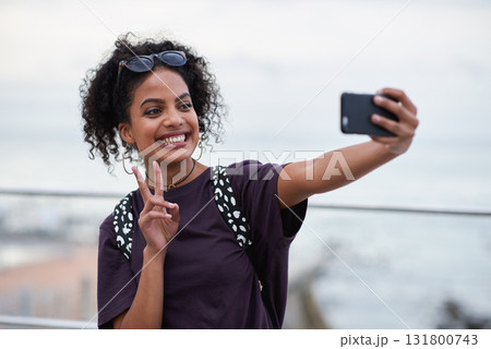 Selfie, peace sign and smile of black woman in city taking pictures for happy memory. Travel, street and female with v hand gesture, having fun and enjoying time while taking photo for social media. 131800743
