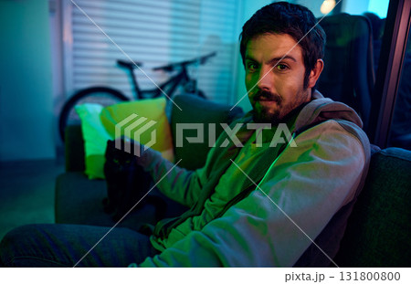 Man, portrait or neon lighting on sofa in living room, house or bachelor pad with feline touching, cat or domestic animal. Person, relax or pet kitten on couch in dark home, garage or night apartment Man, portrait or neon lighting on sofa in living room, house or bachelor pad with feline touching, cat or domestic animal. Person, relax or pet kitten on couch in dark home, garage or night apartment 131800800