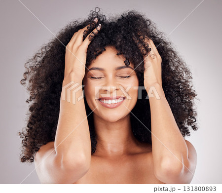 Haircare, beauty and woman with an afro in the studio feeling her hair after a salon treatment. Cosmetic, health and happy female model with a healthy, natural and curly hairstyle by gray background. Haircare, beauty and woman with an afro in the studio feeling her hair after a salon treatment. Cosmetic, health and happy female model with a healthy, natural and curly hairstyle by gray background. 131800893