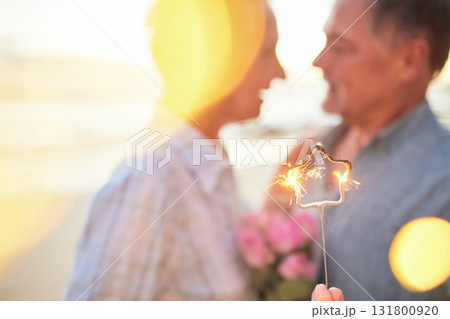 Couple, sparkler and date to celebrate love, birthday and vacation or holiday at beach in summer. Senior man and woman hug outdoor with star and bokeh for sunset dating, marriage or valentines day Couple, sparkler and date to celebrate love, birthday and vacation or holiday at beach in summer. Senior man and woman hug outdoor with star and bokeh for sunset dating, marriage or valentines day 131800920
