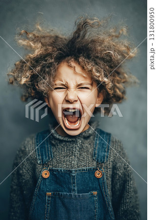 Angry child with wild hair screaming in frustration against a solid background 131800950