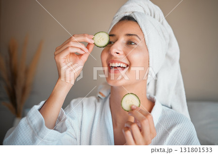 Happy woman, cucumber and natural skincare for beauty, cosmetics or facial treatment at spa. Female smiling and applying vegetable to eyes for organic healthcare, hydration or dermatology at salon 131801533