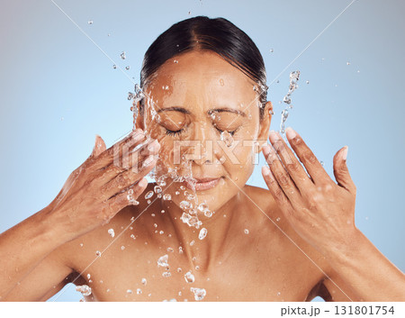 Senior woman, cleaning face and water drops, beauty and sustainable skincare, antiaging on blue background. Facial, healthy skin and eco friendly dermatology, natural cosmetics and female in studio 131801754