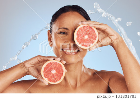 Skincare, portrait and woman with a grapefruit in studio for a natural, beauty and organic face routine. Cosmetic, water splash and mature female model with a citrus fruit isolated by blue background Skincare, portrait and woman with a grapefruit in studio for a natural, beauty and organic face routine. Cosmetic, water splash and mature female model with a citrus fruit isolated by blue background 131801783