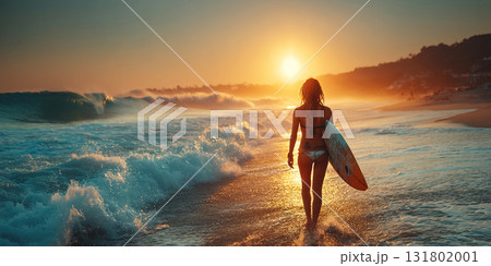 Muscular woman surfer with surfboard walks along beach towards ocean at sunset 131802001