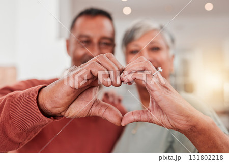 Couple, senior and heart hands in home, love and bonding in retirement together. Romance, hand gesture and elderly man and woman with emoji for care, affection and empathy, commitment and trust. 131802218