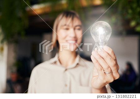 Lightbulb, happy and a woman with light from inspiration, knowledge or ideas at work. Smile, innovation and an employee with power, creativity and energy at a company with optimism and vision 131802221