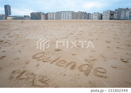 Ostend exclamation word on sea sand. Belgium. Houses, hotel and beautiful walking way. Ostend exclamation word on sea sand. Belgium. Houses, hotel and beautiful walking way. 131802349