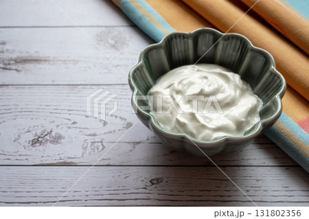 Natural white greek yogurt in porcelain green plate on the wood table with napkin for healthy breakfast. Food concept. Space for text. 131802356