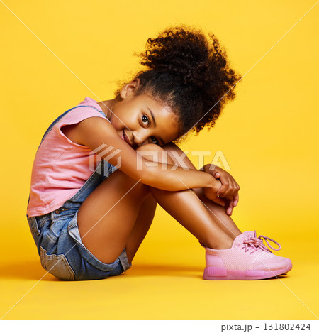 Portrait, shy and girl child on studio floor for children fashion, playful and sweet against yellow background. Face, little and smile by kid with self love, pose and relax while sitting isolated Portrait, shy and girl child on studio floor for children fashion, playful and sweet against yellow background. Face, little and smile by kid with self love, pose and relax while sitting isolated 131802424