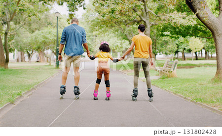 Family, park and holding hands to rollerskate with girl child with care, learning and support. Interracial parents, black man and woman with kid, back and helping hand on road for outdoor holiday Family, park and holding hands to rollerskate with girl child with care, learning and support. Interracial parents, black man and woman with kid, back and helping hand on road for outdoor holiday 131802428