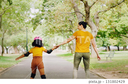 Mother, child and skating with roller skates at nature park for exercise, balance and freedom. Woman and black girl kid or family outdoor to play with helmet for safety, trust and love in summer 131802429
