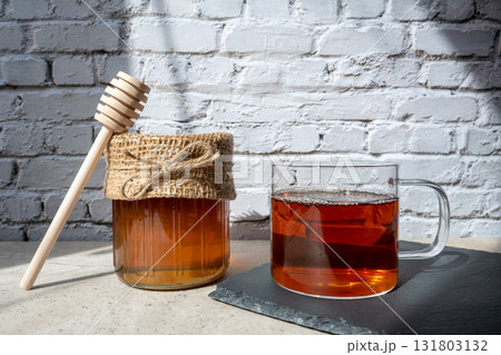 Honey jar with honeycomb, cap of tee and wood spoon stay on the table. Honey jar with honeycomb, cap of tee and wood spoon stay on the table. 131803132