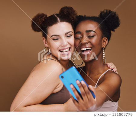 Fashion, selfie and friends with phone smile on brown background for wellness, cosmetics and makeup. Influencer, happy and black women on smartphone for social media content, picture and online post Fashion, selfie and friends with phone smile on brown background for wellness, cosmetics and makeup. Influencer, happy and black women on smartphone for social media content, picture and online post 131803779
