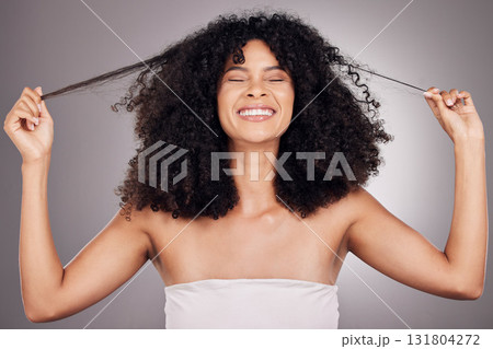 Hair in hands, beauty and face of black woman for wellness, natural growth and curly style. Salon, luxury cosmetics and happy girl smile holding strand for keratin treatment result on gray background Hair in hands, beauty and face of black woman for wellness, natural growth and curly style. Salon, luxury cosmetics and happy girl smile holding strand for keratin treatment result on gray background 131804272