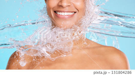 Skincare, clean and smile of a woman with a water splash isolated on a blue background in studio. Health, wellness and mouth, face and happy model on a backdrop for a shower, cleaning and grooming 131804286