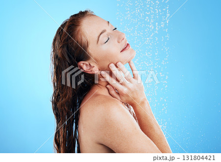 Shower, water and woman in studio, blue background and cleaning for hygiene, wellness and aesthetic health. Happy female model washing with wet drops for beauty, skincare and grooming for self care 131804421