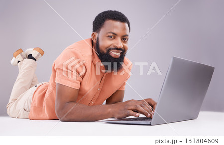 Portrait, black man and laptop on studio floor to search social media, online shopping or subscription download. Happy male model typing on computer technology, internet blogging or elearning website 131804609